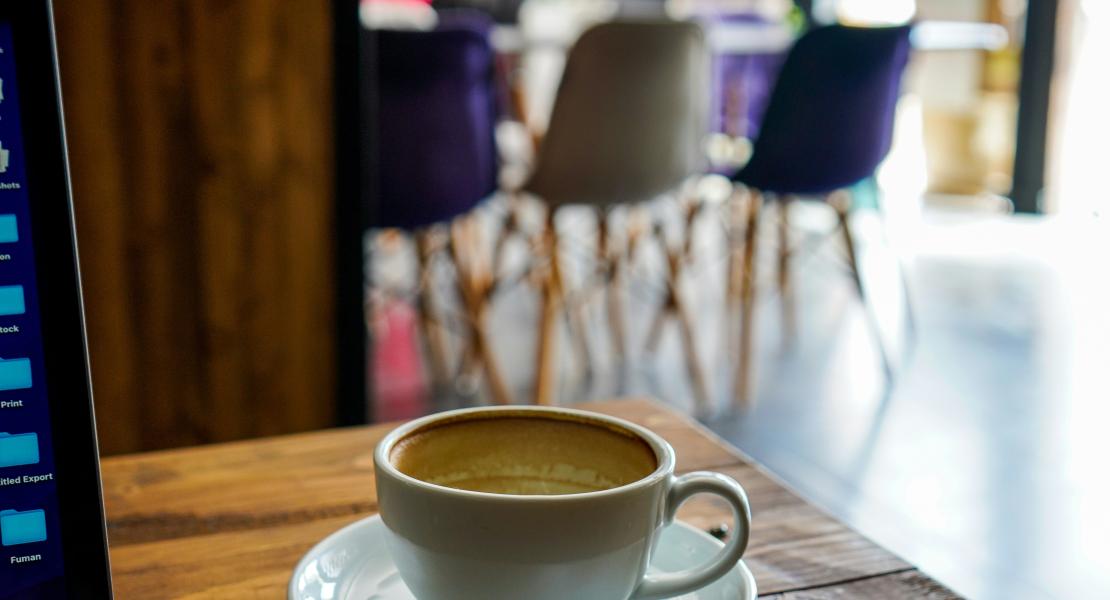 Outdoor terrace with laptop, coffee, and Brussels streetscape.